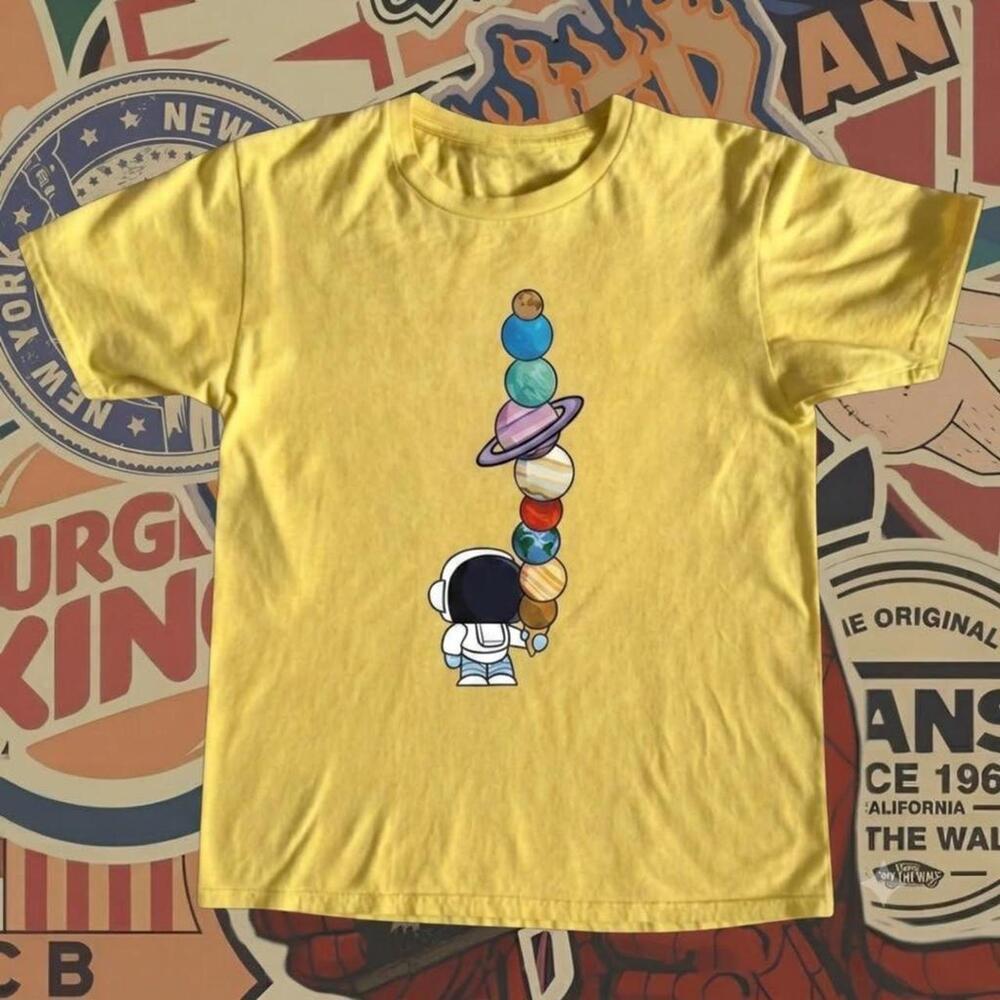 Yellow T-Shirt With Cartoon Astronaut Holding A Stack Of Planets